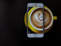 Half a cappuccino in a cup and a smartphone