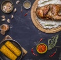 Half chicken with rice on a cutting board with spices, corn and herbs, place for text,frame wooden rustic background top view