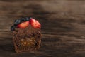 Half of chocolate cupcake with chocolate filling in cut and berries on wooden surface. Fresh chocolate muffin berries Royalty Free Stock Photo