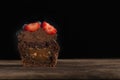 Half chocolate cupcake with filling in cut on wooden surface on black background. Fresh chocolate muffin with berries Royalty Free Stock Photo