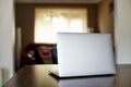 Mockup image of laptop with blank white desktop screen on a wooden table in an ordinary apartment Royalty Free Stock Photo