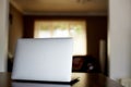 Mockup image of laptop with blank white desktop screen on a wooden table in an ordinary apartment Royalty Free Stock Photo