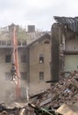 Half collapsed brick house covered in dust and debris with a crasher machine