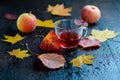 Half-cup hot autumn vitamin herbal tea with autumn leaves and apples