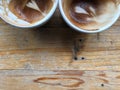 Half cups of two finished hot latte coffee with leftover latte art on grunge pattern wood table Royalty Free Stock Photo