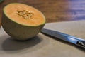 half a cantaloupe with seeds on cutting board with knife Royalty Free Stock Photo