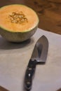 half cantaloupe with seeds on cutting board with knife Royalty Free Stock Photo