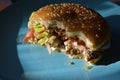 A half-eaten meat Burger with vegetables on a blue plate Royalty Free Stock Photo