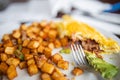 Half-eaten omelette and roasted potatoes on a white plate