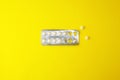 Half-empty blister with white tablets lies on a yellow background. Copy space Royalty Free Stock Photo