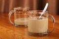 Half-empty and full transparent glass cup with coffee and milk on a wooden table Royalty Free Stock Photo