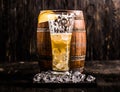 Half empty glass of beer and ice with barrel on the background Royalty Free Stock Photo