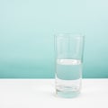 Half empty or half full glass of water on white table. (For positive thinking) Royalty Free Stock Photo