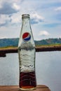 A half empty Pepsi soda bottle against a lake background