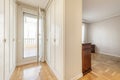 A half-empty room with some old-style wooden furniture, an exit to a corridor with white wooden cabinet doors in Venetian style