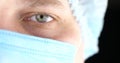 Half face of a doctor in a mask on a black isolated background. The doctor looks into the camera on a black background Royalty Free Stock Photo