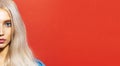 Half face portrait of young beautiful blonde girl with blue eyes. Studio background of red color with copy space. Royalty Free Stock Photo