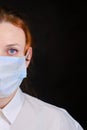 Half face woman in a white shirt and a medical mask on a black background. Concept of people who are isolated in a coronavirus Royalty Free Stock Photo