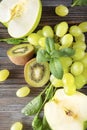 Half a fresh kiwi, green Apple, grape berries, mint sprig on a brown wooden background Royalty Free Stock Photo