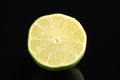 Half of fresh lime on black glass surface, closeup Royalty Free Stock Photo