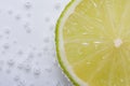 Half fresh lime in water with bubbles Royalty Free Stock Photo
