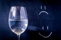 Half-full or half-empty glass of water, with an happy smiley and unhappy smiley, showing optimism or pessimism, concept Royalty Free Stock Photo