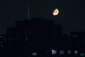 Half of full moon over TV tower and city in warm summer night Royalty Free Stock Photo