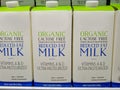 Half gallon cartons of lactose free reduced fat organic milk on fridge shelf.