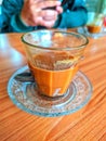 Half glass of cappuccino on front a man with gadget