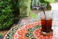 Half Glass of Iced Coffee on Colorful Tiled Table at the Patio