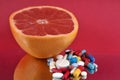 Half grapefruit with assorted drugs on red background Royalty Free Stock Photo