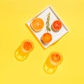 Half of grapefruit and bloody orange, rosemary on a white wooden tray and two glasses of water on bright yellow background. Summer Royalty Free Stock Photo