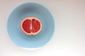 Half of grapefruit on a blue plate on a white background. Top view, copy space. Royalty Free Stock Photo