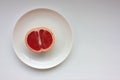 Half of grapefruit on a plate on a white background. Top view, copy space. Royalty Free Stock Photo