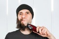 Before - after and half hair. Handsome bearded man trimming his beard with a trimmer
