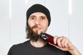 Before - after and half hair. Handsome bearded man trimming his beard with a trimmer