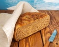 Half homemade freshly baked bread on a rustic table under a linen napkin