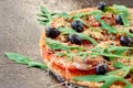 A half of homemade vegetarian pizza with fresh rucola, tomatoes and black olives on the black table close up with free copy space