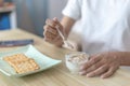 Half-Japanese woman eats yoghurt with cereal for breakfast in room