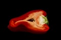 Half a juicy red bell pepper on a black background. Healthy eating and vegetarianism. Close-up Royalty Free Stock Photo