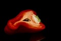 Half a juicy red bell pepper. Healthy and veggie nutrition. Black background with reflection. Close-up Royalty Free Stock Photo