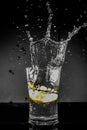 Half Lemon dropped in a glass of water with water splashes with a black to grey background Royalty Free Stock Photo