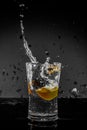 Half Lemon dropped in a glass of water with water splashes with a black to grey background Royalty Free Stock Photo