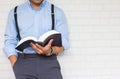 Half-length,Close up Man in blue shirt holding black book of the Bible, Buddhist, Catholic, Christian, prayer,on wall background,