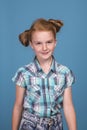 Emotional portrait of a little funny naughty girl with red hair against blue background