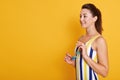 Half length photo of happy young woman with dark hair and ponitail in stylish striped swimsuit and holding sunglasses in her hands Royalty Free Stock Photo