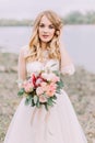 Half-length portrait of the blond bride touching the hairstyle. Beach location. Royalty Free Stock Photo