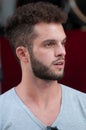 Half-length portrait of a boy with a gray t-shirt with a beard, semi open mouth.