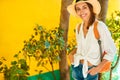 Half length portrait happy woman tourist in straw hat, white shirt smiling and looking to camera, bright yellow wall on Royalty Free Stock Photo