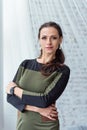 Half-length portrait of a serious brunette in a business dress standing by the window behind white transparent curtain Royalty Free Stock Photo